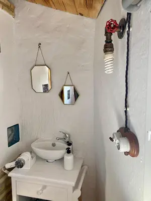 a white bathroom with a sink and a light at El Jardín de Lucas in Arcos de la Frontera