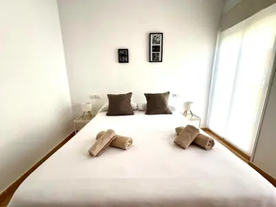 a bedroom with a large white bed with two pillows at Mirador de Doñana Nº 14, Apartamentos Living Sur in Sanlúcar de Barrameda