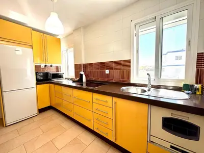 a kitchen with yellow cabinets and a sink and a window at Mirador de Doñana Nº 14, Apartamentos Living Sur in Sanlúcar de Barrameda