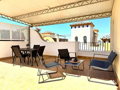 a patio with chairs and a table and a building at Mirador de Doñana Nº 14, Apartamentos Living Sur in Sanlúcar de Barrameda
