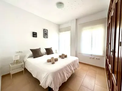 a bedroom with a large white bed with two pillows at Mirador de Doñana Nº 14, Apartamentos Living Sur in Sanlúcar de Barrameda