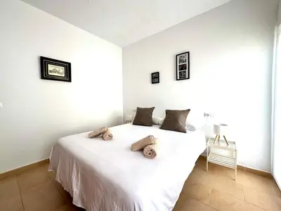 a bedroom with a white bed with towels on it at Mirador de Doñana Nº 14, Apartamentos Living Sur in Sanlúcar de Barrameda