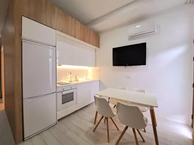 a kitchen with a white refrigerator and a table and chairs at Apartamento Barrosa Pista in Chiclana de la Frontera
