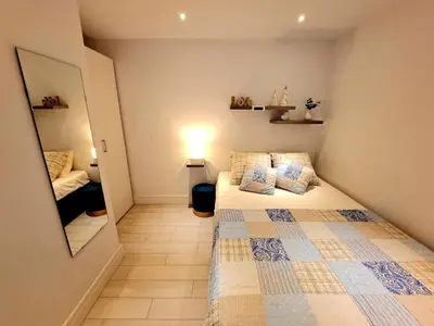 a small bedroom with a bed and a mirror at Apartamento Barrosa Pista in Chiclana de la Frontera