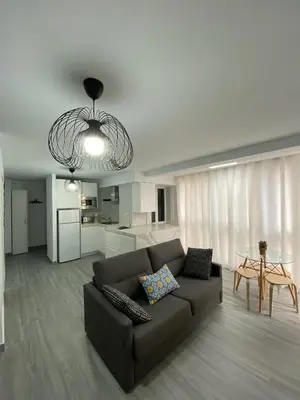 a living room with a brown couch and a kitchen at Molineros Victoria Beach in Cádiz
