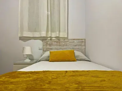 a bedroom with a bed with a yellow pillow on it at Apartamento Alborada - Ole Solutions in Sanlúcar de Barrameda