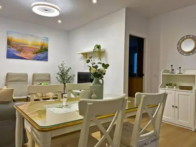 a dining room and living room with a table and chairs at Apartamento Alborada - Ole Solutions in Sanlúcar de Barrameda