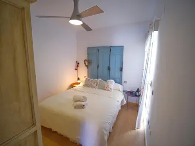 a bedroom with a white bed with a ceiling fan at Apartamento Residencial Al Andalus 117, La Barrosa, Chiclana, Incluye parking a unos metros del mar in Chiclana de la Frontera