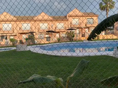 a resort with a swimming pool behind a fence at Apartamento Residencial Al Andalus 117, La Barrosa, Chiclana, Incluye parking a unos metros del mar in Chiclana de la Frontera