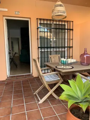 a patio with a table and chairs and a potted plant at Apartamento Residencial Al Andalus 117, La Barrosa, Chiclana, Incluye parking a unos metros del mar in Chiclana de la Frontera