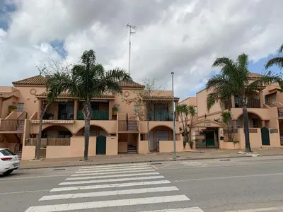 a building with palm trees in front of a street at Apartamento Residencial Al Andalus 117, La Barrosa, Chiclana, Incluye parking a unos metros del mar in Chiclana de la Frontera
