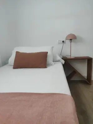 a bed with a brown pillow and a table at La Terraza de Natipao in Rota
