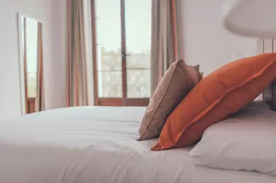 two orange pillows sitting on a bed with a window at Apartamentos Puerta Sevilla in Jerez de la Frontera