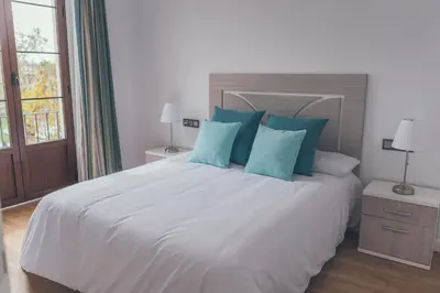 a bedroom with a large white bed with blue pillows at Apartamentos Puerta Sevilla in Jerez de la Frontera
