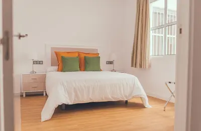 a bedroom with a bed with orange and green pillows at Apartamentos Puerta Sevilla in Jerez de la Frontera