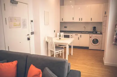 a living room with a couch and a table and a kitchen at Apartamentos Puerta Sevilla in Jerez de la Frontera
