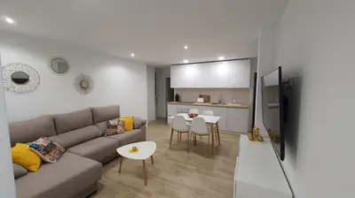 a living room with a couch and a table and a kitchen at APARTAMENTO A PIE DE PLAYA. in Cádiz