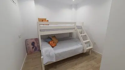 a bunk bed in a room with a ladder at APARTAMENTO A PIE DE PLAYA. in Cádiz