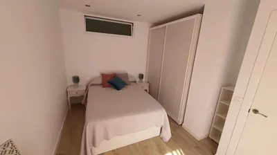 a small white bedroom with a bed and a window at APARTAMENTO A PIE DE PLAYA. in Cádiz