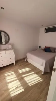 a bedroom with a bed and a dresser and a mirror at APARTAMENTO A PIE DE PLAYA. in Cádiz