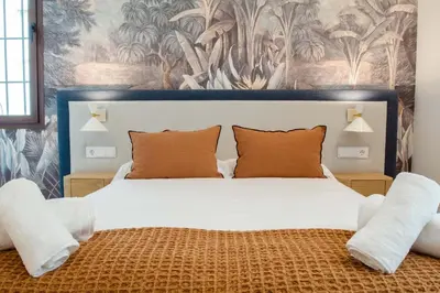 a bedroom with a large white bed with orange pillows at CISNES PALACE in Sanlúcar de Barrameda