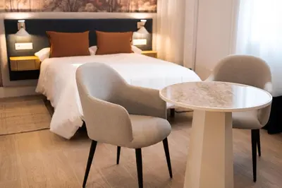 a bedroom with a bed and two chairs and a table at CISNES PALACE in Sanlúcar de Barrameda