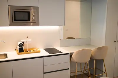 a kitchen with white cabinets and a microwave and two stools at CISNES PALACE in Sanlúcar de Barrameda