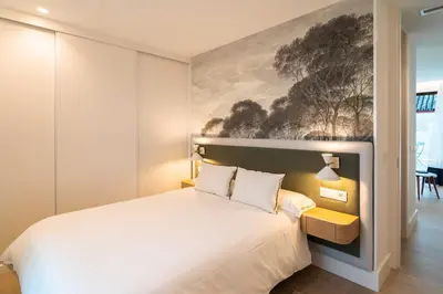 a bedroom with a white bed and a painting on the wall at CISNES PALACE in Sanlúcar de Barrameda
