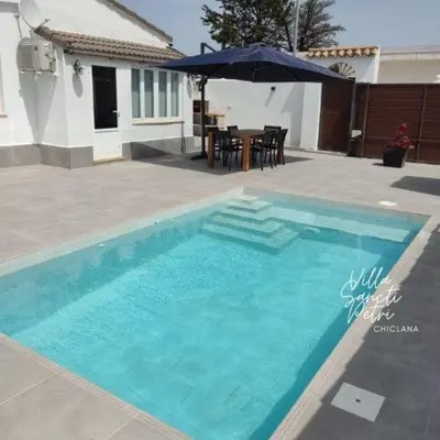a blue swimming pool with a table and an umbrella at VILLA SANCTI PETRI in Chiclana de la Frontera