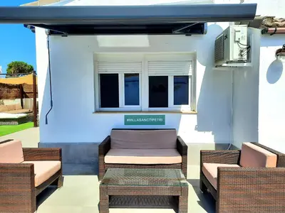 a patio with two chairs and a table and a window at VILLA SANCTI PETRI in Chiclana de la Frontera