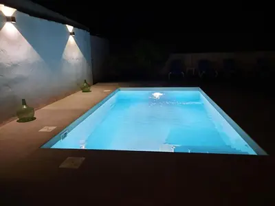 a large blue swimming pool in a backyard at night at VILLA SANCTI PETRI in Chiclana de la Frontera