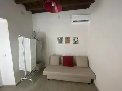 a white room with a couch with a red pillow at Apartamento La Flamencura in Jerez de la Frontera