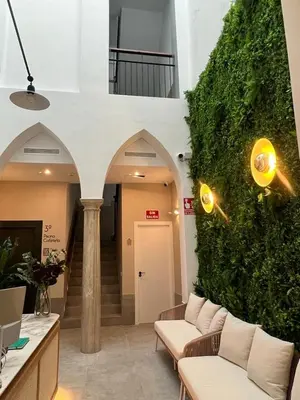 a lobby with a green wall with couches in a building at Soho Boutique Columela in Cádiz