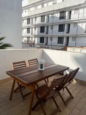 a wooden table and chairs on a balcony with a building at Apartamento Centro Playa in Sanlúcar de Barrameda
