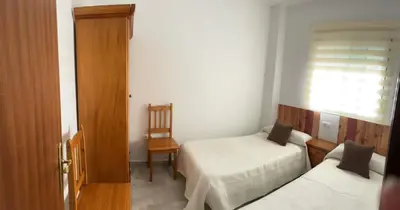a small bedroom with two beds and a window at Apartamento Centro Playa in Sanlúcar de Barrameda