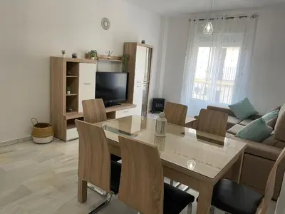 a living room with a table and chairs and a couch at Apartamento Centro Playa in Sanlúcar de Barrameda