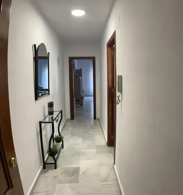 a hallway with white walls and a television on a wall at Apartamento Centro Playa in Sanlúcar de Barrameda