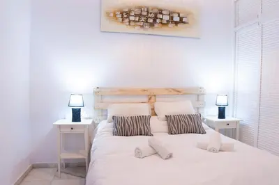 a bedroom with a white bed with two tables and two lamps at CDZ - Suarez de Salazar 1 y 2 in Cádiz