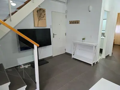 a living room with a television and a staircase at Atico Capuchinos in Sanlúcar de Barrameda