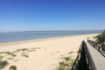 a boardwalk on a beach next to the water at Atico Capuchinos in Sanlúcar de Barrameda