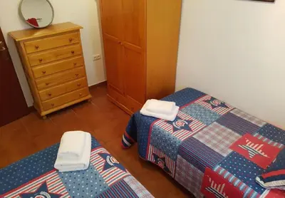 a bedroom with two twin beds and a dresser at El Cano Playa Victoria Grupo AC Gestion in Cádiz