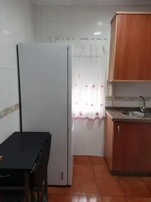 a kitchen with a refrigerator and a table and a sink at El Cano Playa Victoria Grupo AC Gestion in Cádiz