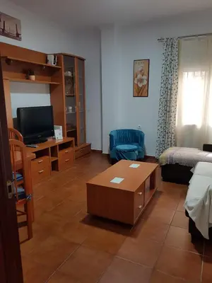 a living room with a tv and a couch and a table at El Cano Playa Victoria Grupo AC Gestion in Cádiz