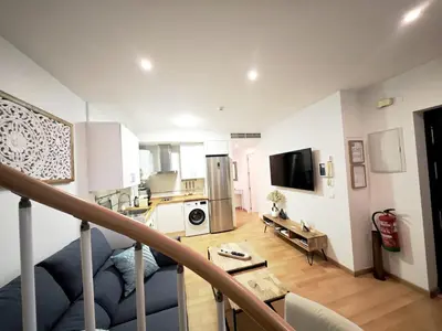 a living room with a staircase leading to a kitchen at La Terraza de Gades Little Apartments in Cádiz