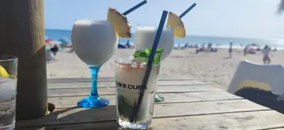 two drinks sitting on a table at the beach at BRISAMAR Rota ATLÁNTICO apartment in Rota