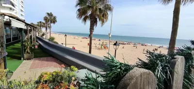 a slide on a beach with people on the beach at BRISAMAR Rota ATLÁNTICO apartment in Rota