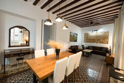 a dining room and living room with a wooden table and chairs at Casa del Sur in Cádiz