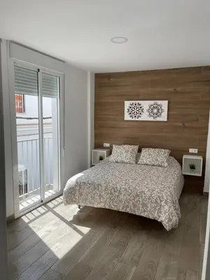 a bedroom with a bed and a large window at apartamentos Bandera in Jerez de la Frontera