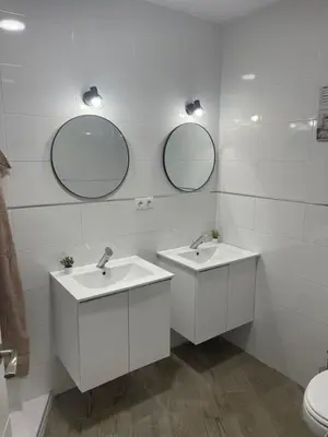 a bathroom with two sinks and two mirrors at apartamentos Bandera in Jerez de la Frontera