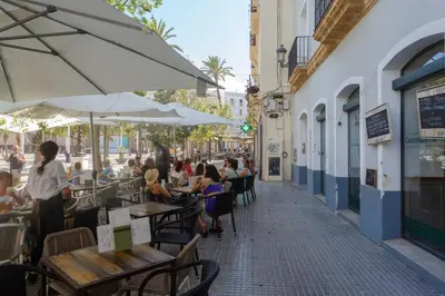 a group of people sitting at tables at an outdoor restaurant at Apartamentos El Capitan Veneno by Cadiz4Rentals in Cádiz